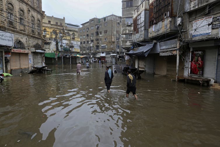 people wade through a flooded city street