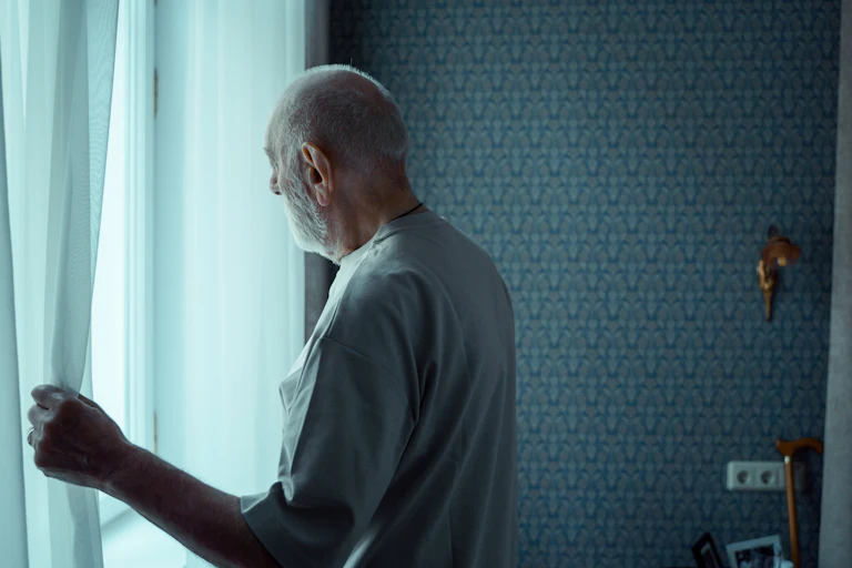 An older man looks out the window.