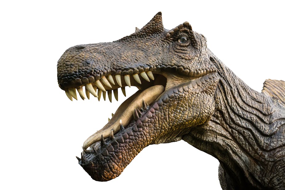 A brown-ish dinosaur with sharp teeth and bony protruding "eyebrows" appears to grin at the viewer