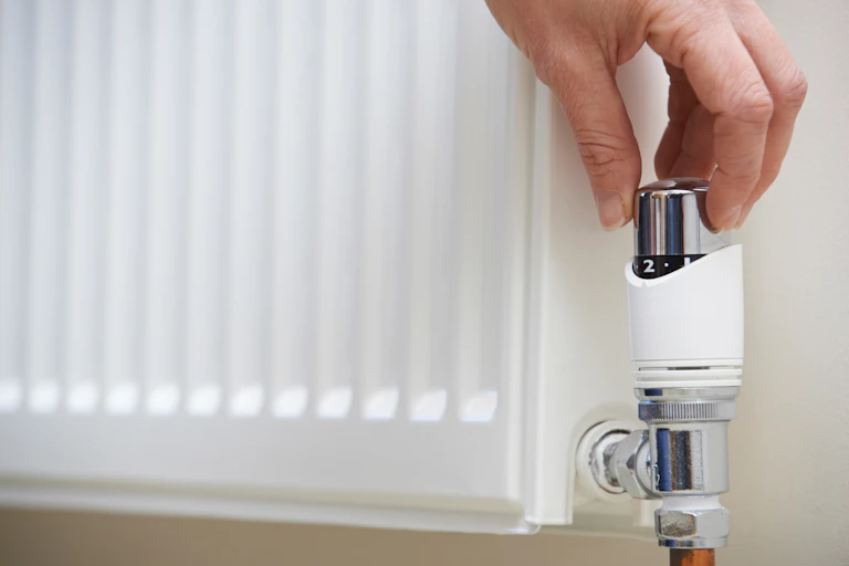 Person turning down the heat on a radiator