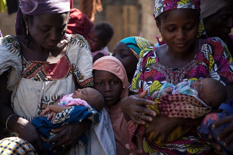 Two women holding new born babies.