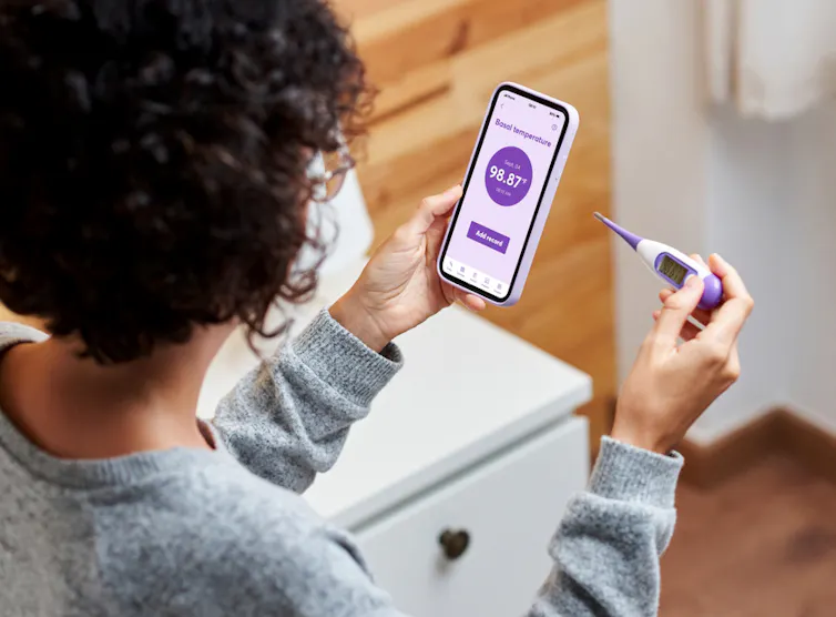 Une jeune femme a pris sa température et s’apprête à l’entrer dans son application