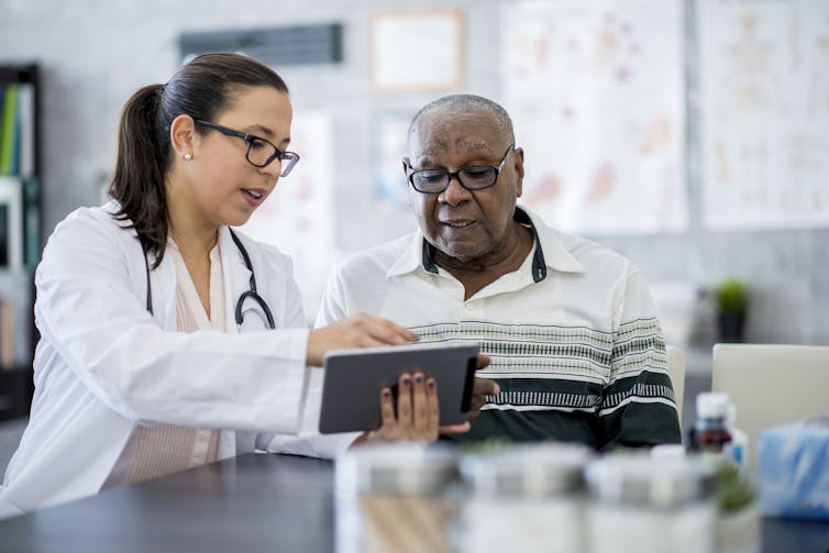 Clinician showing clipboard to patient in exam room