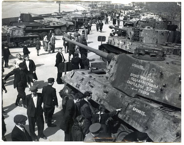 People in civilian clothes look at rows and rows of tanks.