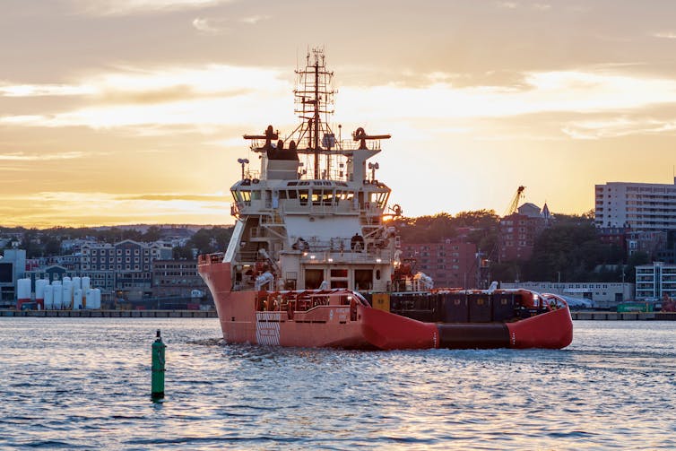 An orange boat enters a port