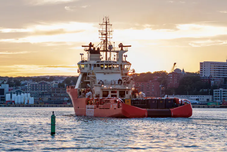 An orange boat enters a port