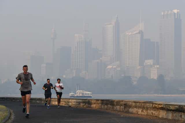 Three runners by Sydney Harbour in smoke haze