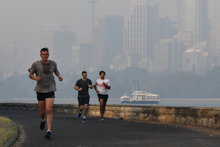 Three runners by Sydney Harbour in smoke haze