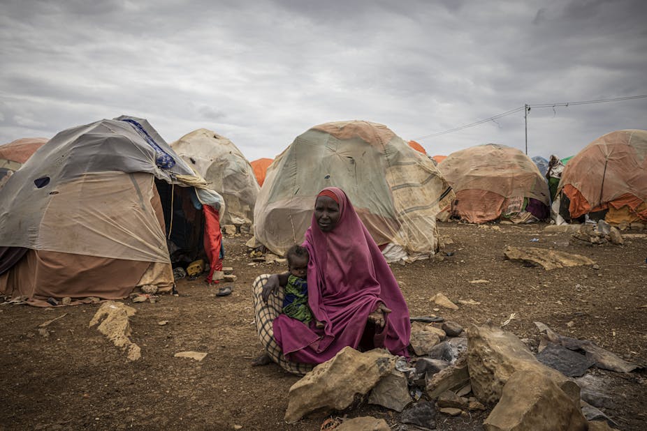A woman sits outside her tent with her daughter Najima Barre in a displacement camp for people impacted by drought.