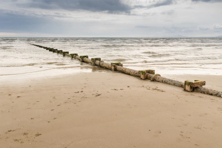 A sewage discharge pipe leading out to sea on a UK beach.