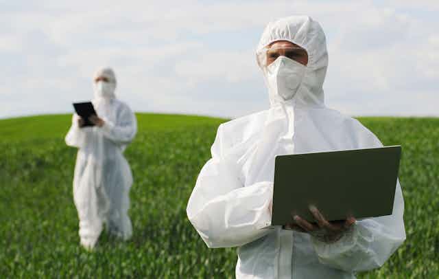 Two scientists in a field with laptops