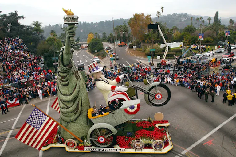 Paman Sam mengendarai sepeda motor di sebelah Lady Liberty di sebuah parade