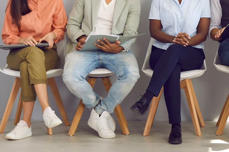 A row of people sitting holding books and folders.