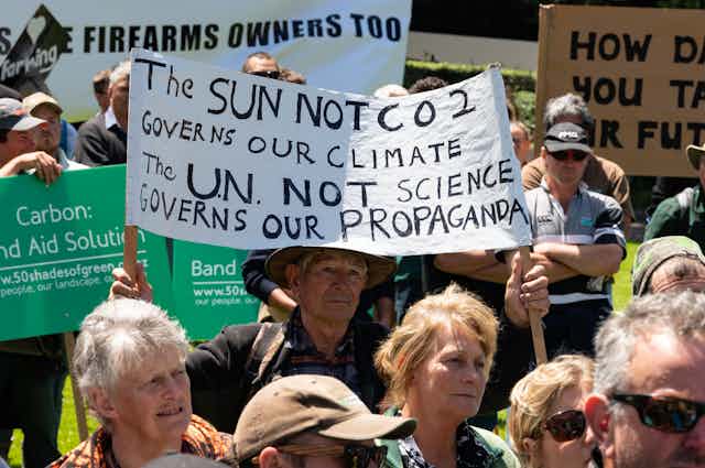rally of people holding signs voicing scepticism about climate change