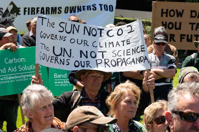 rally of people holding signs voicing scepticism about climate change