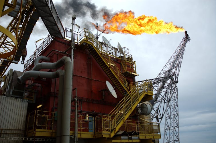 An offshore oil rig with a flare emerging from one of its chimneys.