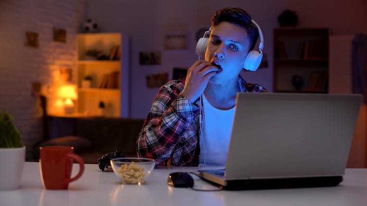 Teenage boy stares at laptop screen late at night