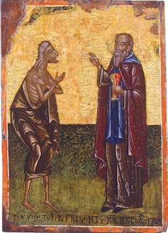 A gold and green religious icon depicts a man in a robe extending Holy Communion to a woman in a tattered robe.