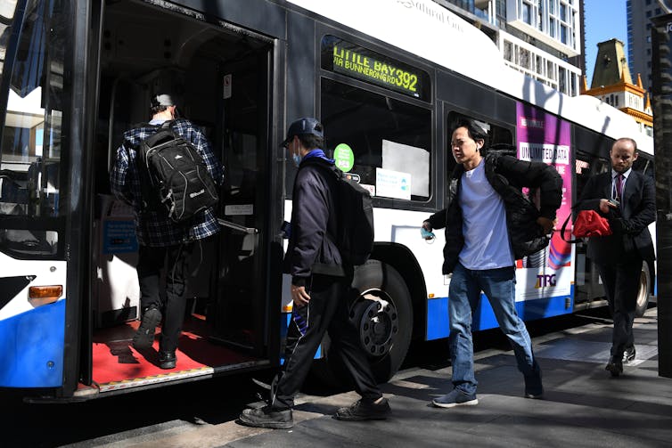 people line up to board bus