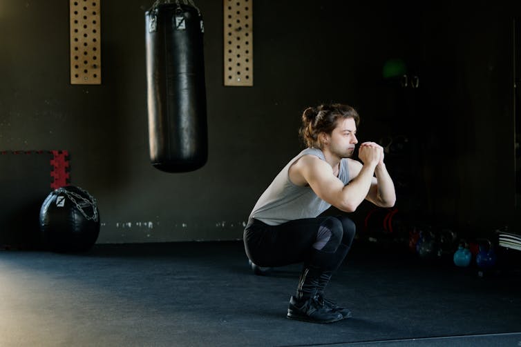 man does squat exercise in gym