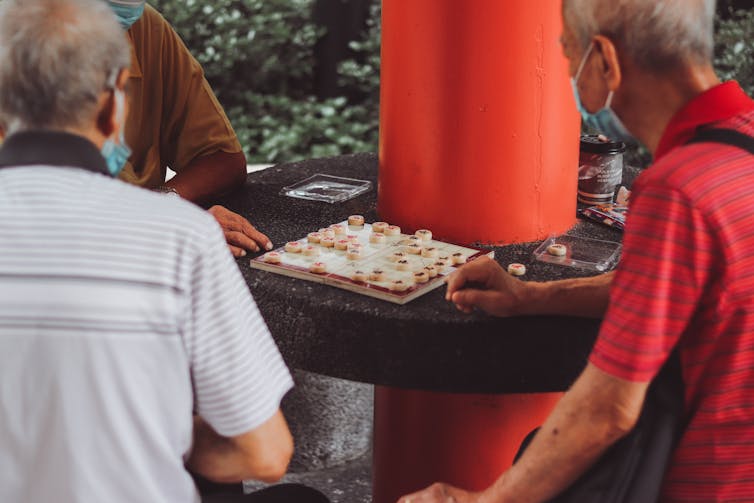 Older people play a board game.