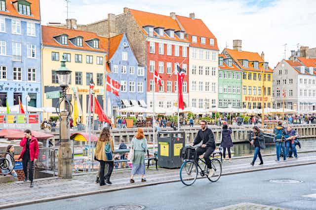 People walking and cycling alongside a canal in Copenhagen, Denmark.