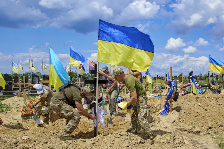 Comrades set up a national flag on the grave during a funeral in Kharkiv, June 2022.