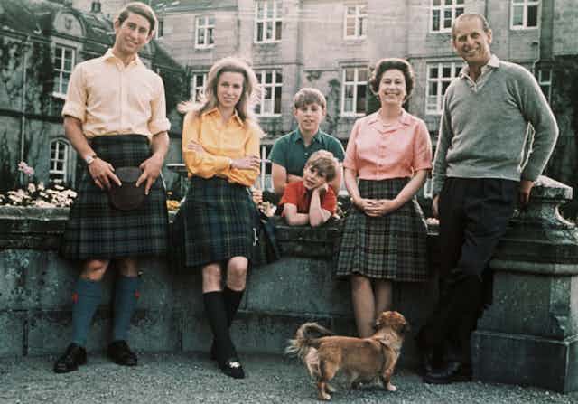 Members of the Royal family in tartan pose outdoors with a corgi.