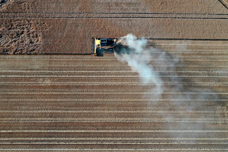 An aerial view of a tractor driving through a field