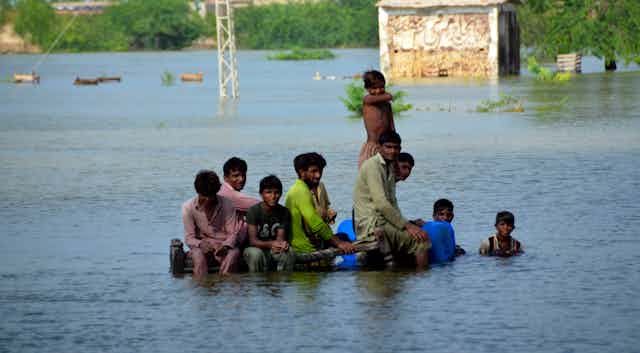 A group of men sit in floodwater in Pakistan's southwestern Balochistan province, Sept. 3, 2022.