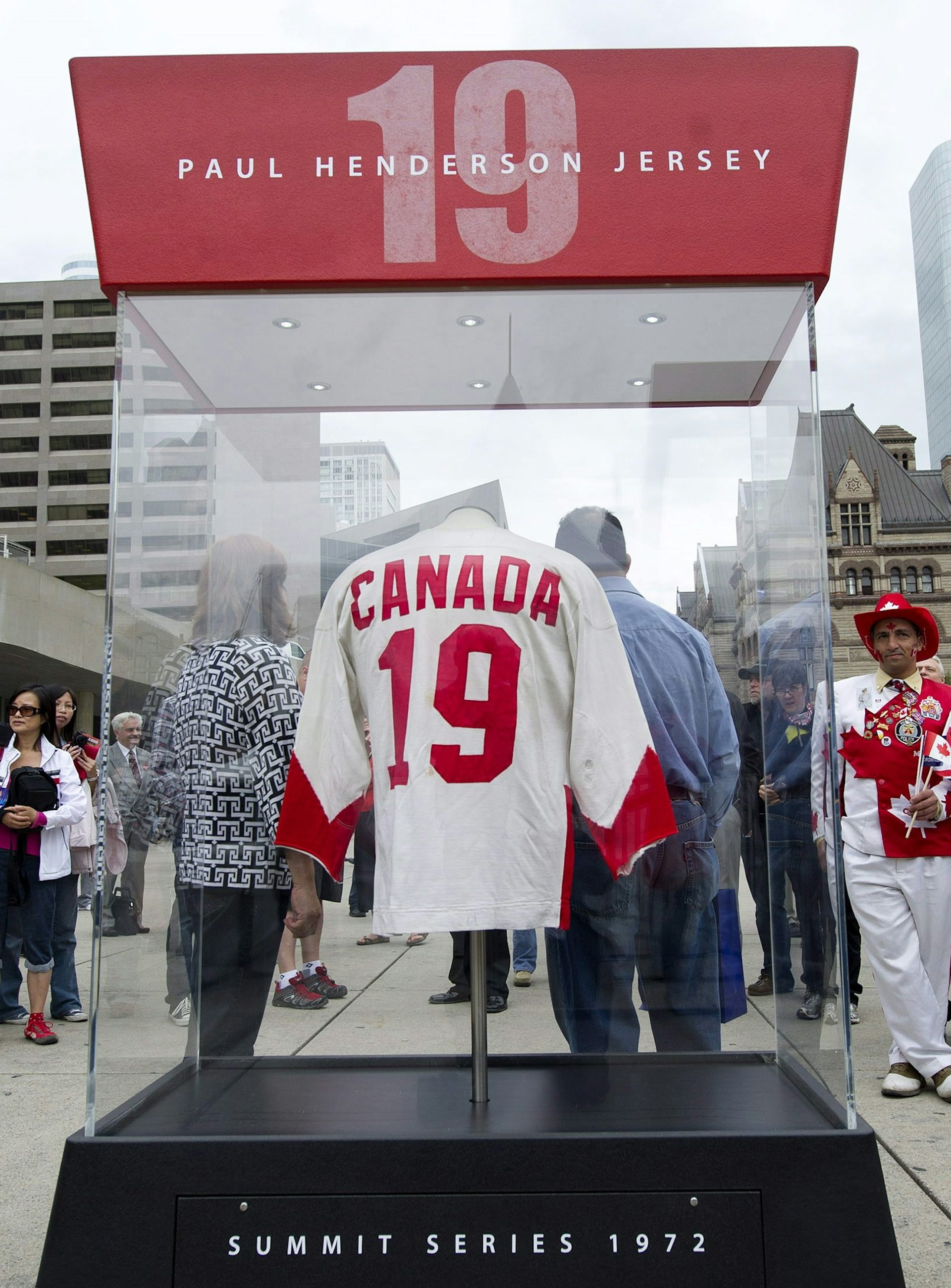 A white and red Canadian hockey jersey with the number 19 on the back is seen in a clear display case.