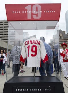 A white and red Canadian hockey jersey with the number 19 on the back is seen in a clear display case