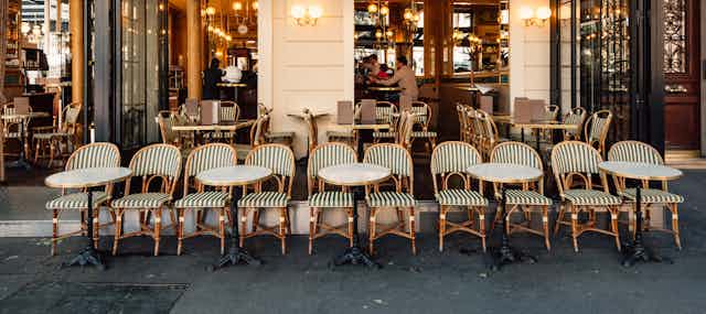 chairs and tables lined up outside a Paris cafe. 