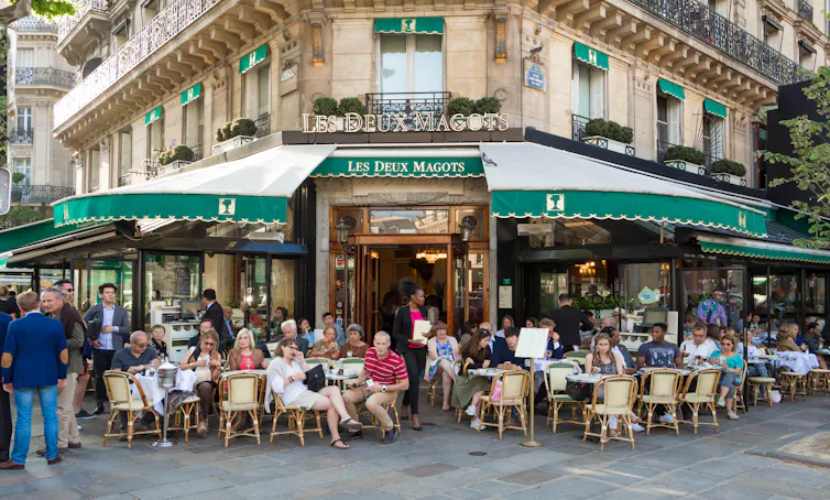 People sitting on chairs outside a café.