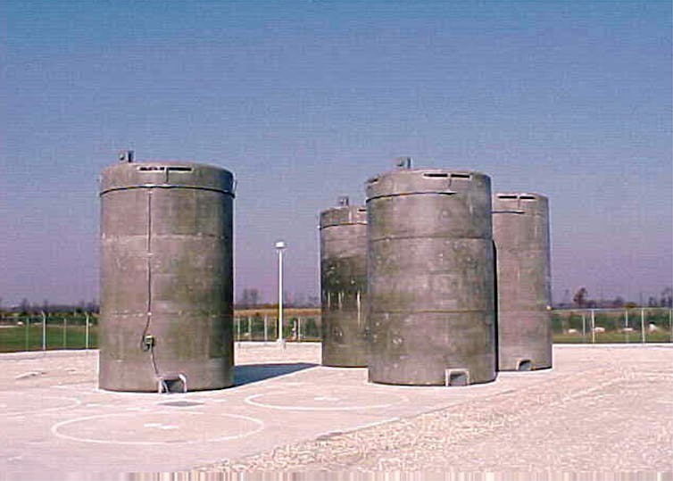 four large concrete cylinders on a concrete slab