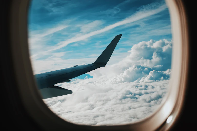 An aeroplane wing in blue sky visible from plane window