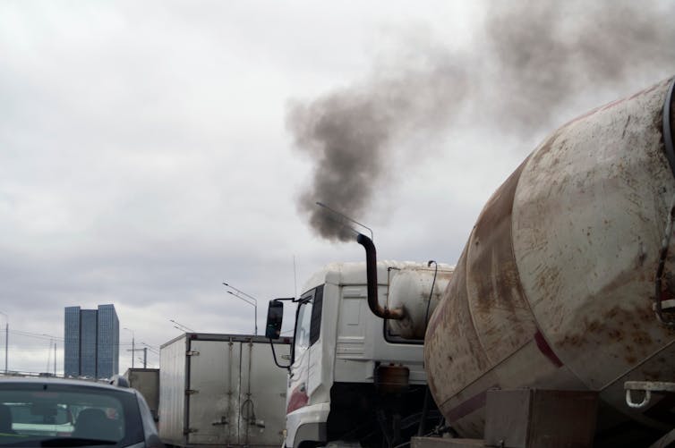 A truck in heavy traffic belches smoke