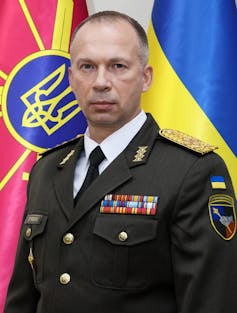 Man in military uniform in front of Ukrainian flag