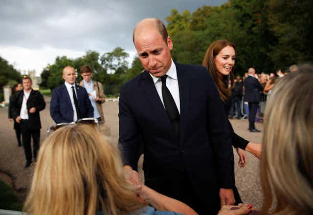 Prince William and Kate Middleton greet the public outside Buckingham Palace.