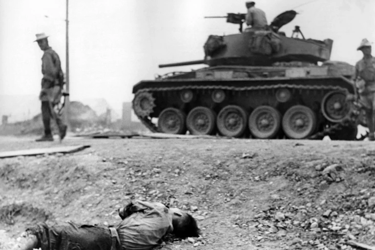 Des militaires en char passent à côté du corps d'un soldat mort
