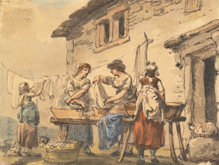 Women seen doing washing over tubs in the street.