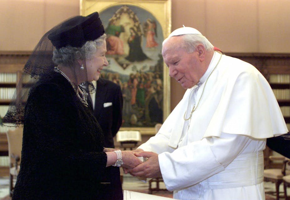 Queen Elizabeth II, dressed in black, shaking hands with Pope John Paul II in October 2000.
