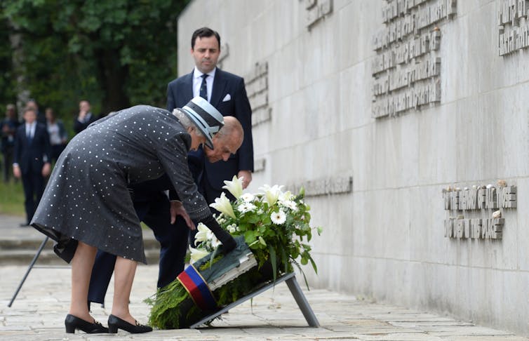 Queen Elizabeth II and Prince Philip bending down to pay homage and lay a wreath at the Nazi concentration camp Bergen-Belsen on June 26, 2015.