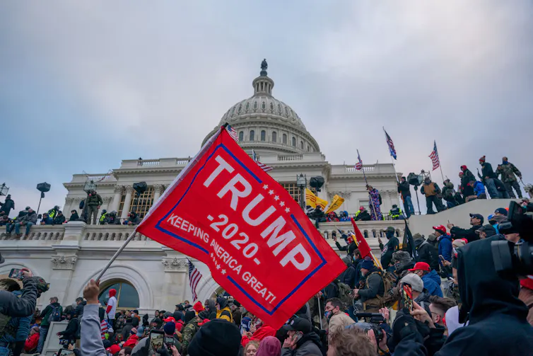 A Trump supporter waves a MAGA flag in front of the U.S. Capitol building.