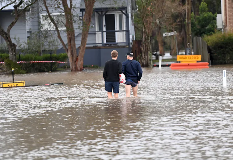 Two people wade in floodwater