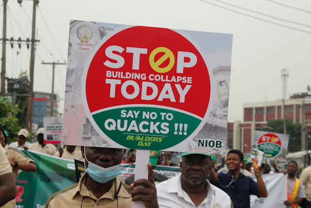 Man holds a sign protesting building collapse 