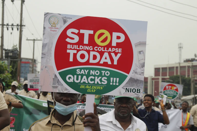 Man holds a sign protesting building collapse