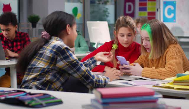 Teenagers looking at phone in class