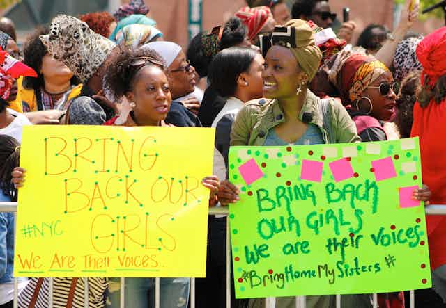 Two women with placards saying: Bring back our girls