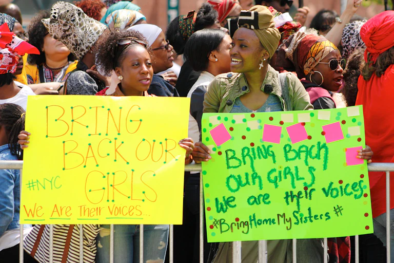 Two women with placards saying: Bring back our girls